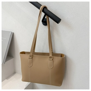 Detail of camel tote bag featuring white contrast stitching and gold metal rings