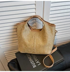 Detail of woven straw bucket bag with brown leather handles and gold metal hardware