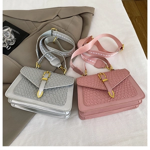 Close-up of woven leather square bag with golden buckle and patterned canvas strap