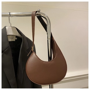 Detail of a brown crescent shoulder bag with golden metal hardware and a smooth leather finish