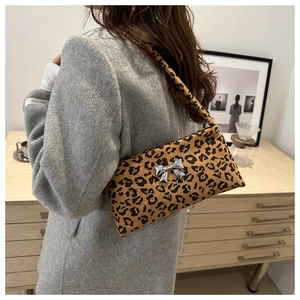 Close-up of leopard print shoulder bag with metallic bow detail on a stylish wool coat