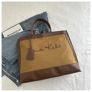 Close-up of khaki canvas tote bag with Frida Kahlo script and brown leather handles