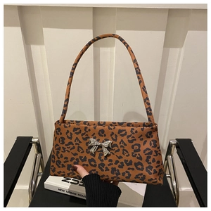 Detail of leopard print shoulder bag featuring a decorative silver metal bow clasp