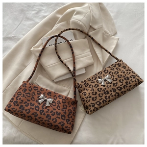 Close-up of leopard print underarm bags with metallic butterfly accents and strap details