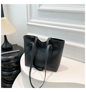 Detail view of smooth black PU leather tote bag with embossed logo on a display stand