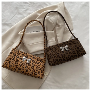 Detail of leopard print underarm bags with metallic silver butterfly buckles on fabric