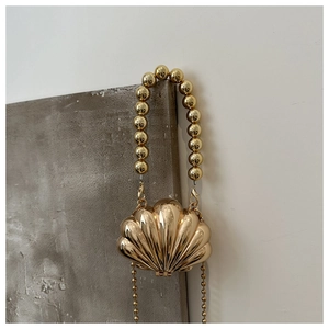 Detailed view of a gold shell-shaped evening clutch with beaded handle and chain