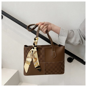 Detailed view of brown tote bag featuring checkered texture and printed silk scarf handle