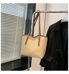 Detailed shot of beige leather tote bag with brown trim and adjustable metal buckles