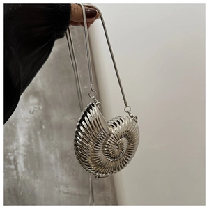Close-up of silver conch-shaped metal clutch bag with spiral texture and chain strap