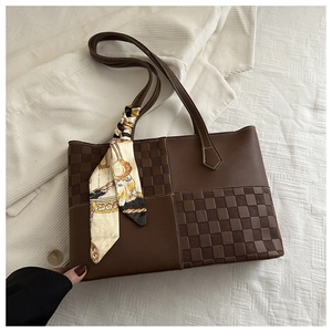 Close-up of dark brown leather tote featuring checkered texture and decorative silk scarf