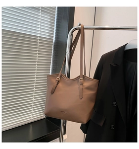 Close-up of brown leather tote bag with FASHION & BAGS text and buckle details