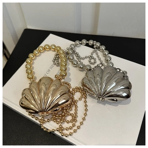 Detail of shell-shaped metallic crossbody bags in gold and silver with bead handles