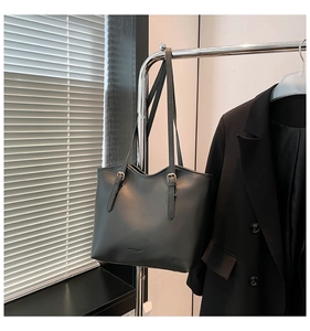 Detail of minimalist black matte leather tote bag hanging on stainless steel rack