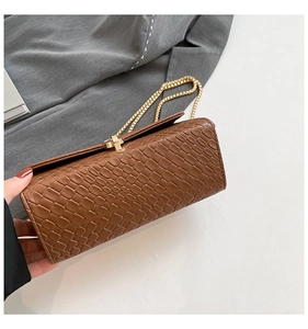 Detail of dark brown faux-crocodile texture on shoulder bag with gold metal clasp