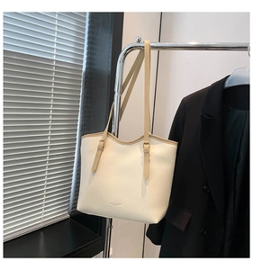 Detail of cream tote bag with fine brown straps and embossed leather logo text