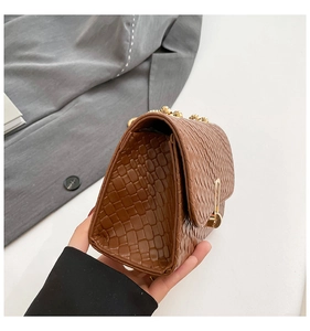 Detail view of woven brown handbag showing side structure and gold metal hardware