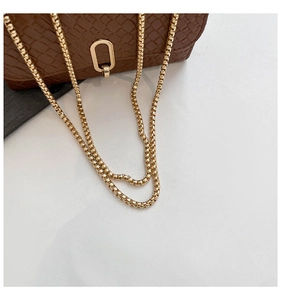 Detail showing brown textured leather texture with gold metal chain strap on a bag