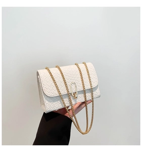 Detail of white woven texture shoulder bag with gold metal chain and oval twist lock