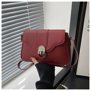 Dettaglio borsa a tracolla bordeaux con chiusura girevole argento e tracolla sottile in pelle