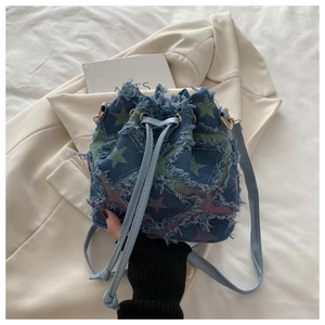 Macro view of blue denim bucket bag with colorful star patches and frayed edge texture