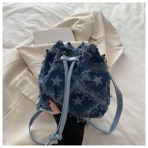 Detailed view of blue denim bucket bag with star patterns and frayed edges design