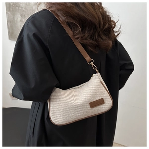 Detail of canvas shoulder bag with brown leather trim and golden metal hooks