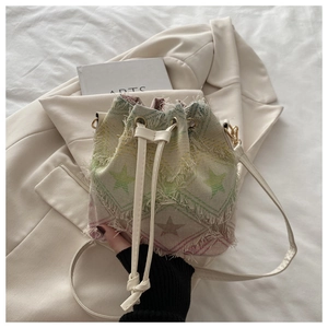 Detail of denim bucket bag with rainbow star patterns and white crossbody strap