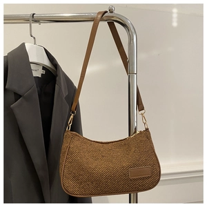 Detail of brown woven hobo bag featuring fashion leather label and adjustable shoulder strap