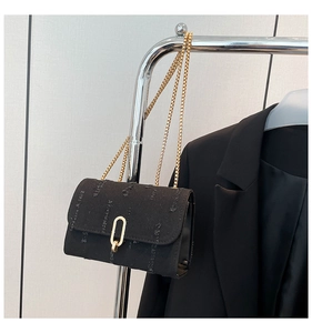 Close-up of black denim chain bag with gold oval lock and textured distressed finish