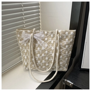 Détail de la broderie fleurie blanche et du nœud en dentelle sur ce sac fourre-tout