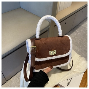 Detail of brown suede crossbody bag with white fleece trim and gold turn-lock closure