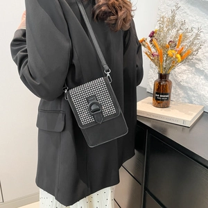 Sac bandoulière noir tendance pour téléphone avec clous argentés porté par un mannequin