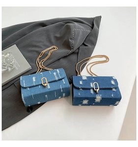 Detailed macro view of denim chain bags showing distressed texture and gold oval buckles