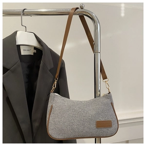 Detail of grey twill fabric and brown leather trim on a minimalist shoulder bag