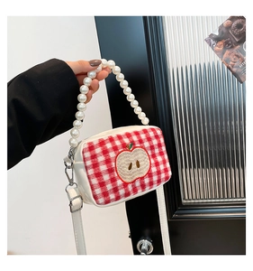 Detail of red checkered vanity bag with apple embroidery and pearl handle strap