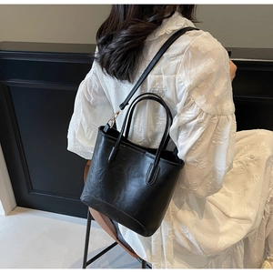 Detail of black leather bucket bag with pebble texture and adjustable shoulder strap