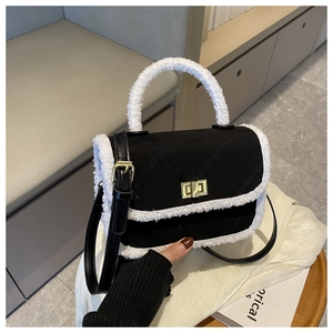 Detail of quilted black handbag with white faux fur trim and golden metal turn lock