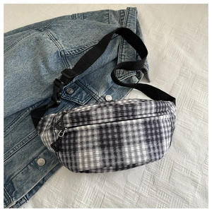 Detail of checkered waist bag with dual zippers and adjustable strap on denim