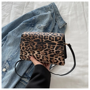 Dettaglio borsa baguette leopardata con tracolla nera e chiusura a patta superiore
