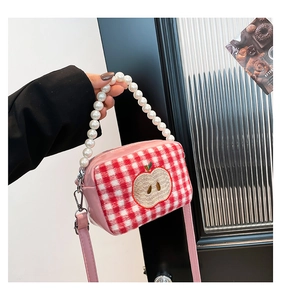 Detail of red checkered mini bag with apple embroidery and elegant pearl bead handle