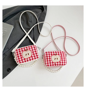 Close-up of red checkered crossbody bags with apple embroidery and pearl handle detail