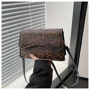 Dettaglio della borsa a spalla leopardata con tracolla in pelle nera sul davanzale