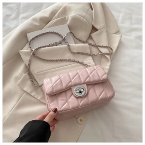Detailed view of light pink quilted crossbody bag with metal chain strap and turn-lock