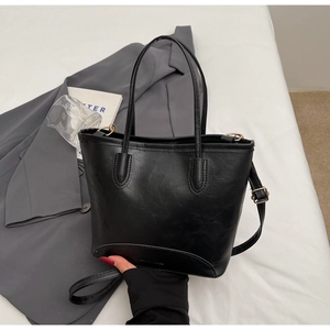 Detail of black textured faux leather tote bag with gold hardware and fashion embossing