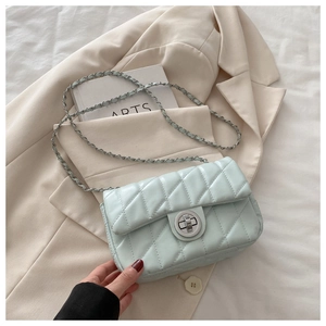 Detail of mint green quilted crossbody bag with silver turn-lock and chain strap