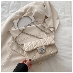 Detailed close-up of cream quilted crossbody bag with silver chain and metal turn-lock