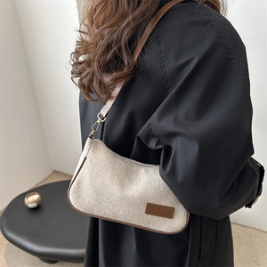 Retro cream canvas shoulder bag with brown leather trim worn by model in minimalist setting