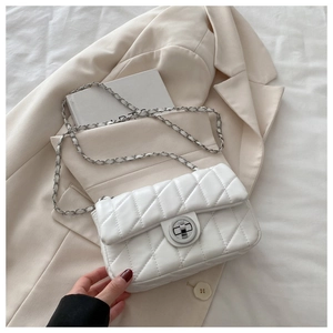 Detail of white quilted crossbody bag with silver chain strap and metal turn lock closure