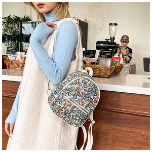 Floral embroidery mini backpack on model in a cafe setting with leather trim and straps
